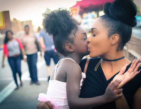 Mother holding and kissing daughter.